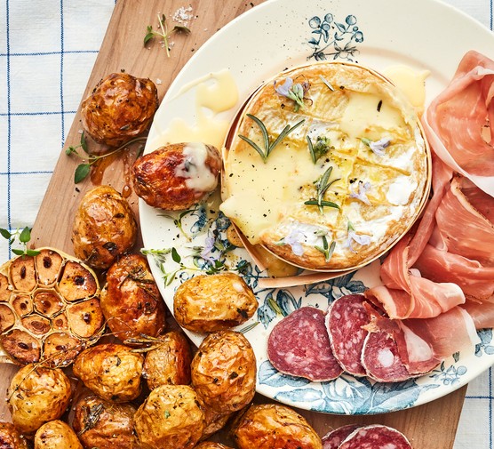 Baked-cheese-with-roasted-garlic-Jersey-Royals Baked camembert on a plate with sliced meats jersey royal potatoes