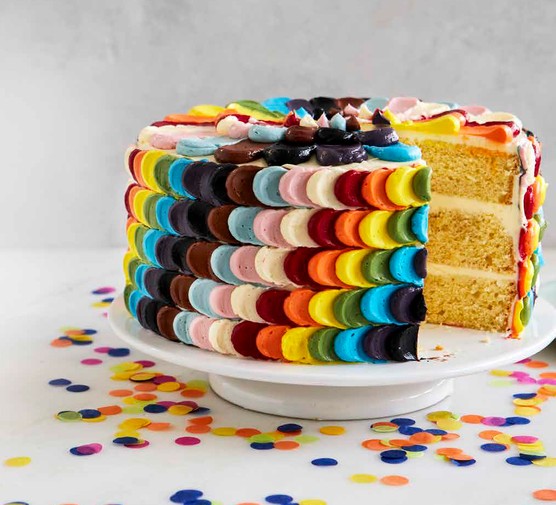 Pride Cake A cake with multiple coloured icing sits on a cake stand surrounded by confetti